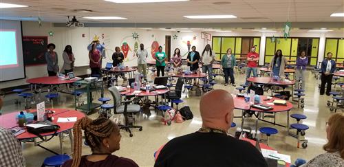 Teachers at PLA@103 standing in a "community circle" discussing pans for the new year. 