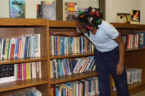Student looking through books at the TLJ library. 